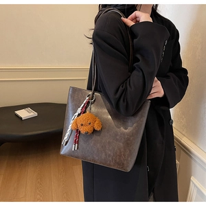 Dettaglio borsa tote vintage in pelle marrone con ciondolo a cucciolo e foulard di seta a righe