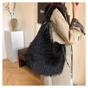Detail of a plush black faux fur tote bag featuring a decorative ribbon bow accent