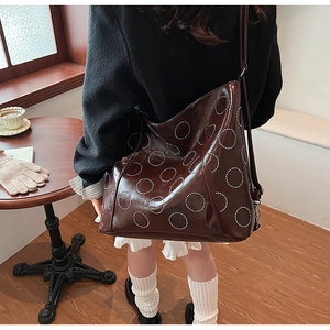 Detail of dark brown tote bag with white dotted ring patterns in a cafe setting