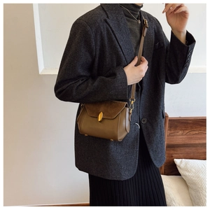 Detail of vintage brown leather crossbody bag with elegant gold droplet buckle and strap