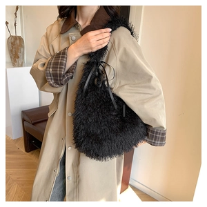 Detail of black faux fur shoulder bag with soft plush texture and ribbon bow decoration