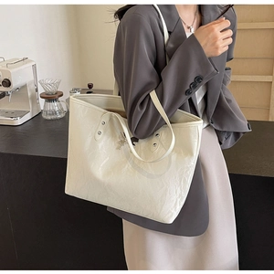 Detail of cream tote bag with crinkle texture and silver butterfly ornament in cafe