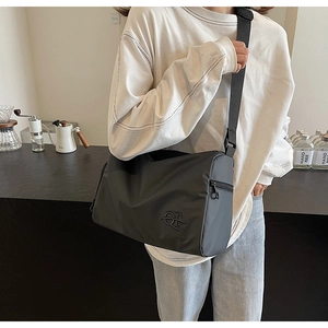 Détail du sac cylindrique en nylon noir avec bandoulière réglable sur un mannequin lifestyle