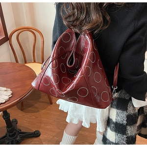 Macro shot of burgundy large tote bag with silver metallic studs in a trendy setup