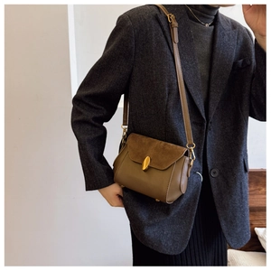 Detail of vintage crossbody bag in olive leather and suede featuring gold oval clasp buckle