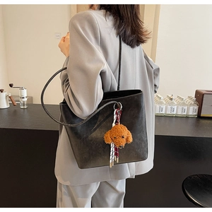 Foto lifestyle di una grande borsa tote nera con un simpatico ciondolo orsetto marrone