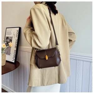 Detail of dark brown leather crossbody bag with vintage golden leaf twist lock and pleated sides