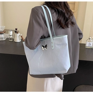Close-up of light blue tote bag with metallic butterfly buckle and pleated leather texture