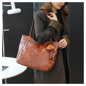 Dettaglio della borsa tote marrone vintage con logo PonPon inciso e ciondolo a orsetto
