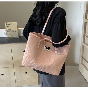 Detail of pink tote bag showing wrinkled texture and silver butterfly metal buckle detail