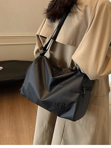 Grand sac à bandoulière en nylon noir avec logo brodé porté avec un trench-coat kaki élégant