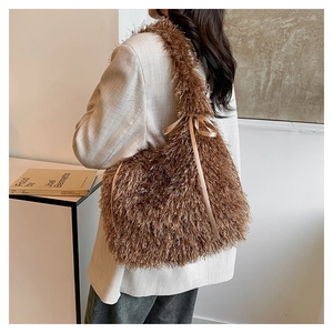 Detail of plush brown shoulder bag with long faux fur texture and a satin ribbon bow