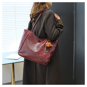 Dettaglio della grande borsa tote in pelle rosso scuro con ciondolo a forma di orsetto
