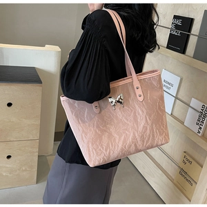 Detail of light pink tote bag with textured fabric and metallic butterfly ornament