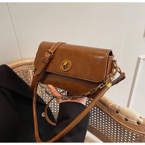 Detail of vintage brown shoulder bag with golden round rotary lock and dual straps