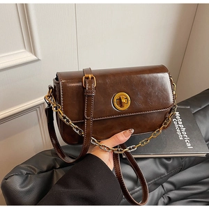 Close-up of vintage dark brown handbag with gold rotary lock and two-tone chain strap