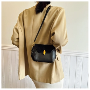 Close-up of black crossbody bag with gold pebble lock and premium leather texture