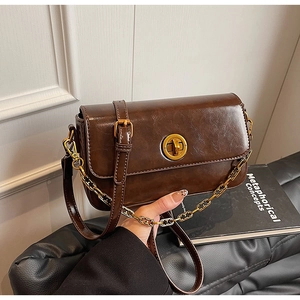 Detail of vintage coffee leather handbag with gold twist lock and chain strap