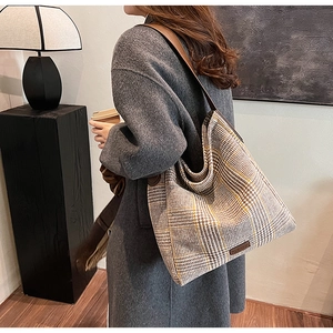 Detail of vintage plaid tote bag with brown leather shoulder strap on a winter wool coat