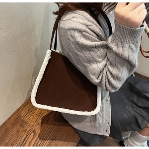 Detail of a brown suede tote bag with white faux shearling trim worn by a model