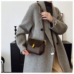 Detail of vintage brown leather crossbody bag with suede flap and gold metal lock clasp