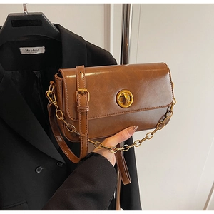 Detail of vintage brown leather handbag with gold twist lock and stylish chain strap