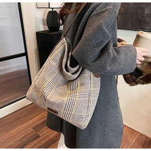 Close-up of houndstooth wool tote bag with leather straps on a model in a cozy room
