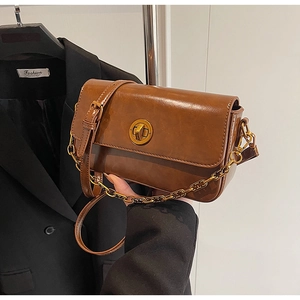 Detail of vintage brown leather handbag with gold circular twist lock and chain strap