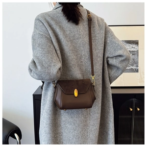 Detail view of vintage dark brown crossbody bag with gold metal clasp and mixed textures
