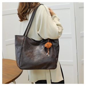 Dettaglio della borsa tote vintage in pelle marrone con ciondolo a orsetto e logo