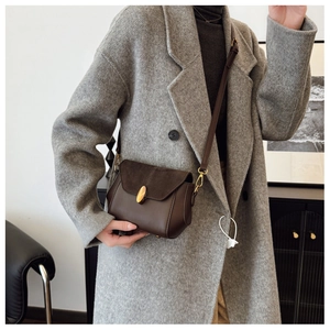 Detail of vintage brown crossbody bag with gold oval lock and suede texture flap