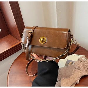 Close-up of retro dark brown leather crossbody bag with gold metallic swivel lock buckle