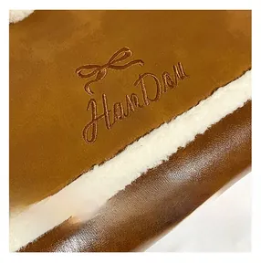 Detailed close-up of premium brown PU leather with soft white wool edge and gold embroidery