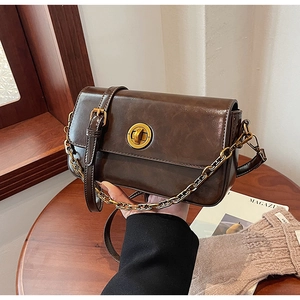 Close-up of vintage dark brown faux leather bag with gold circular twist-lock buckle