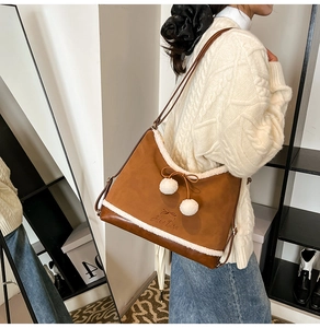 Detailed close-up of brown frosted leather bucket bag with white faux fur trim and pom-poms