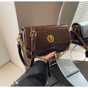 Detail of vintage brown oil wax leather bag with golden circular twist lock and chain strap