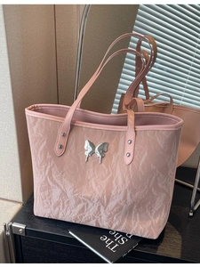 Pink tote bag with pleated texture and silver butterfly ornament in a home setting