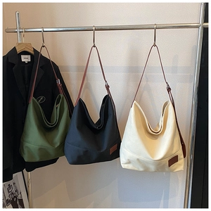 Detailed view of large canvas tote bags in three colors with leather straps on a display