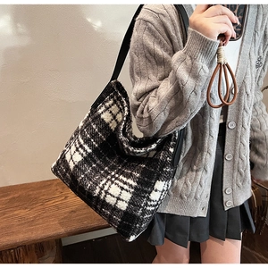 Detail of black and white checkered tote bag with wide leather strap on model