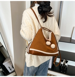 Close-up of brown PU leather handbag with white faux fur trim and cute pom-poms