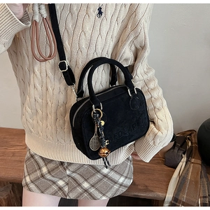 Detalle de mini bolso de ante negro con letras en relieve y colgante de raqueta