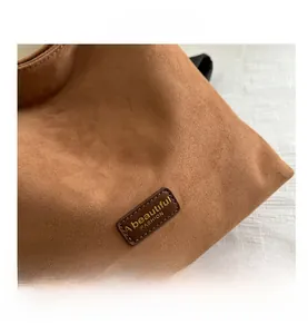 Detail of caramel suede texture and a leather patch with embossed fashion text