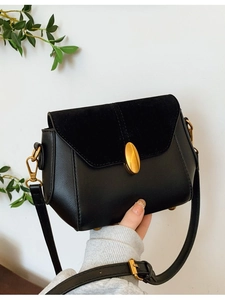Retro black leather crossbody bag with suede flap and gold oval buckle on white background