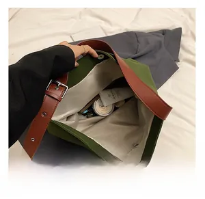 Detail view of large olive canvas tote bag with brown leather strap and inner zipper pocket