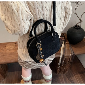 Bolso bandolera de cuero negro mate con grabado de letras y colgantes usado por modelo