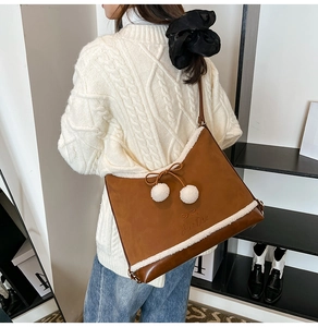 Close-up of caramel faux suede bucket bag with white fur trim and plush pom-poms worn by model