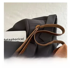 Detail of adjustable long shoulder strap on brown suede bucket bag over a blazer