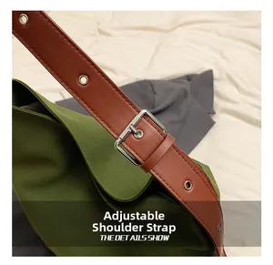 Detail of dark green canvas bag showing adjustable brown leather strap and silver metal buckle
