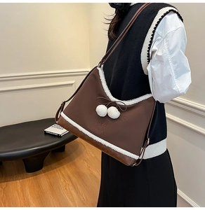 Detail view of brown crossbody bucket bag with white faux fur trim and bow accents