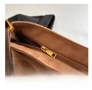 Detail view of smooth golden metal zipper and brown suede texture on a vintage tote bag